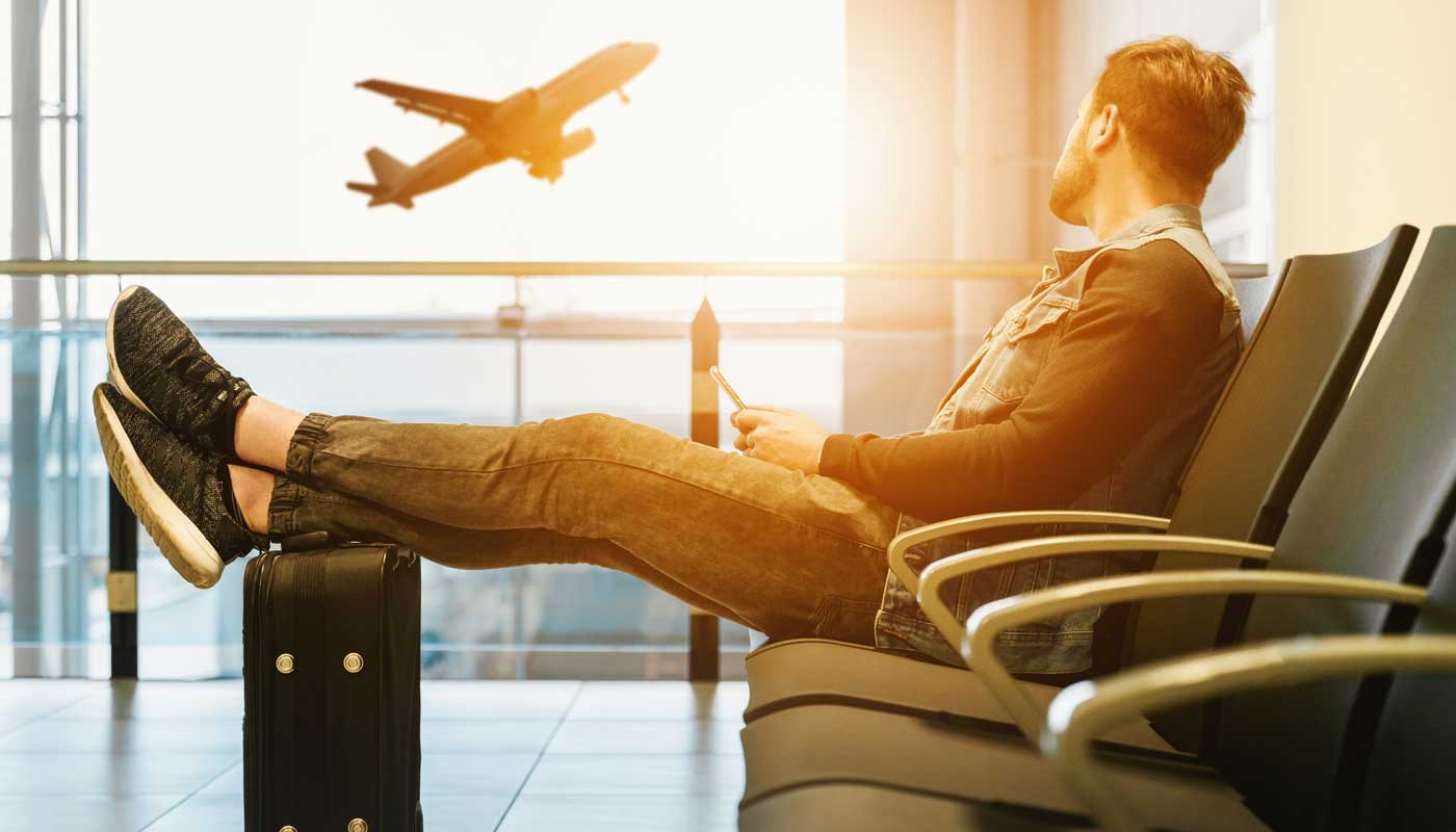 Zanzibar Experts Mann saß auf Stuhl mit Füßen oben in einem Flughafen mit Flugzeug ein Flugzeug abheben im Hintergrund